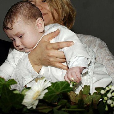 Ein Baby wird bei der Taufe von seiner Mutter gehalten.