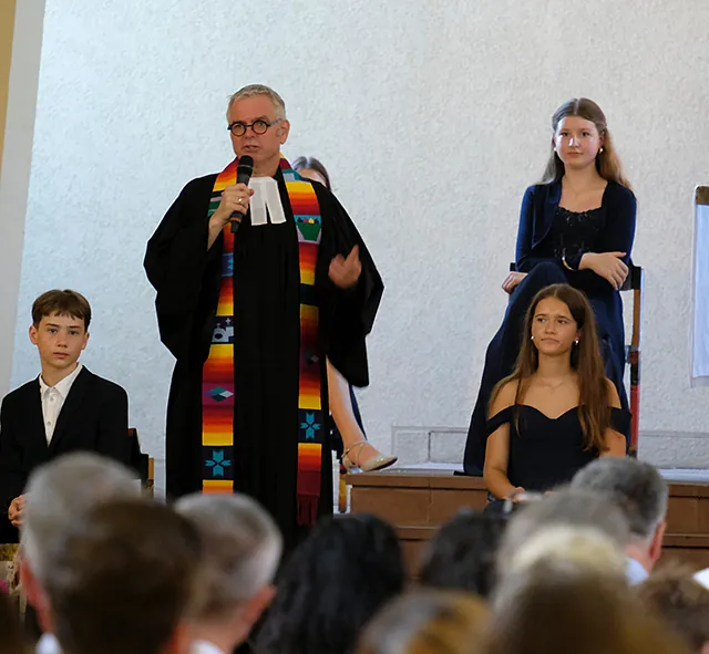 Pfarrer und Konfirmand*innen in der Kirche