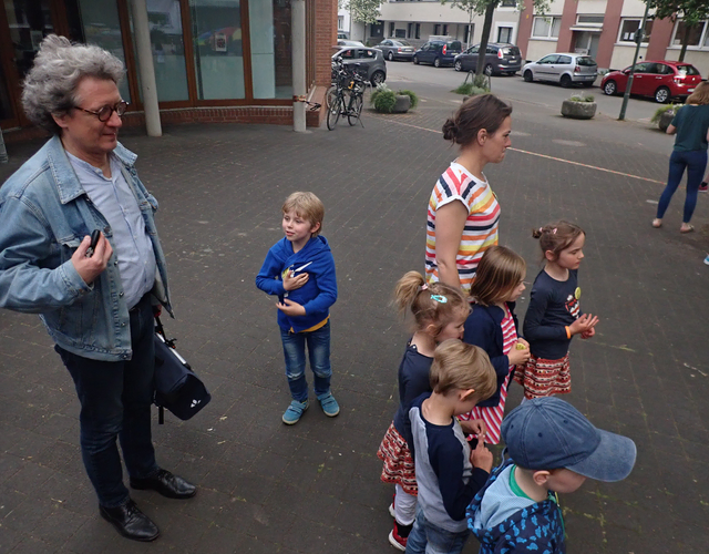 Kinder und Erwachsene stehen bei Gruppenveranstaltung draußen auf dem Gehweg.