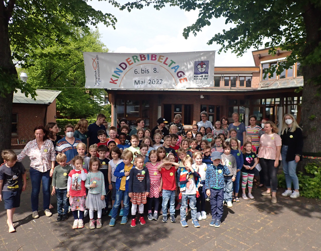 Große Gruppe aus Kindern und Erwachsenen posiert draußen bei Kinderbibeltage.