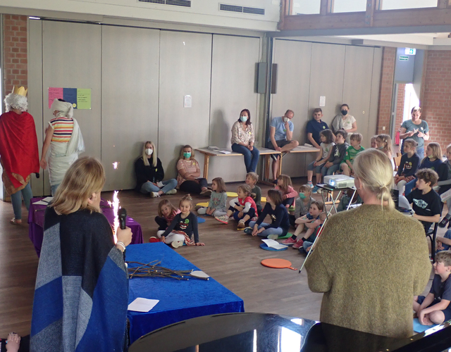 Kinder schauen Theaterstück mit Kostümen und Wunderkerzen, Erwachsene stehen daneben.