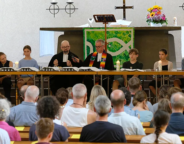 Pfarrer und Konfirmand*innen in der Kirche